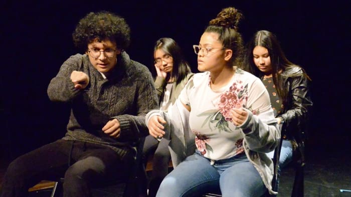 teenage kids sitting in chairs on stage