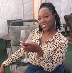 Tiffany smiles, holding a glass of wine